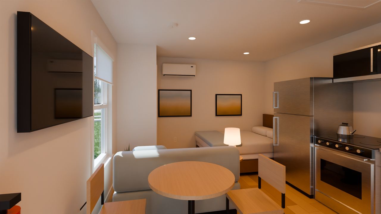 Concept render of a studio with a round table and a loveseat, the bed in the far corner, the indoor unit of the heat pump high on the end wall, and the kitchen along the back wall.