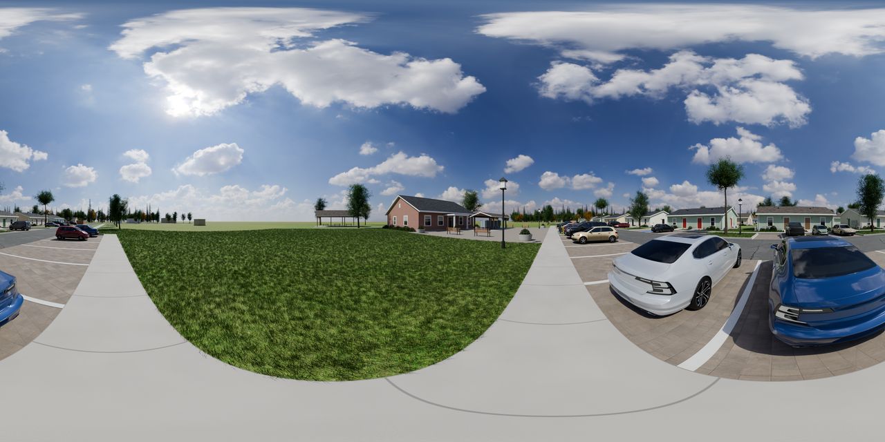 A brick community building with a covered pavilion beside it, a lawn, a sidewalk and parked cars.